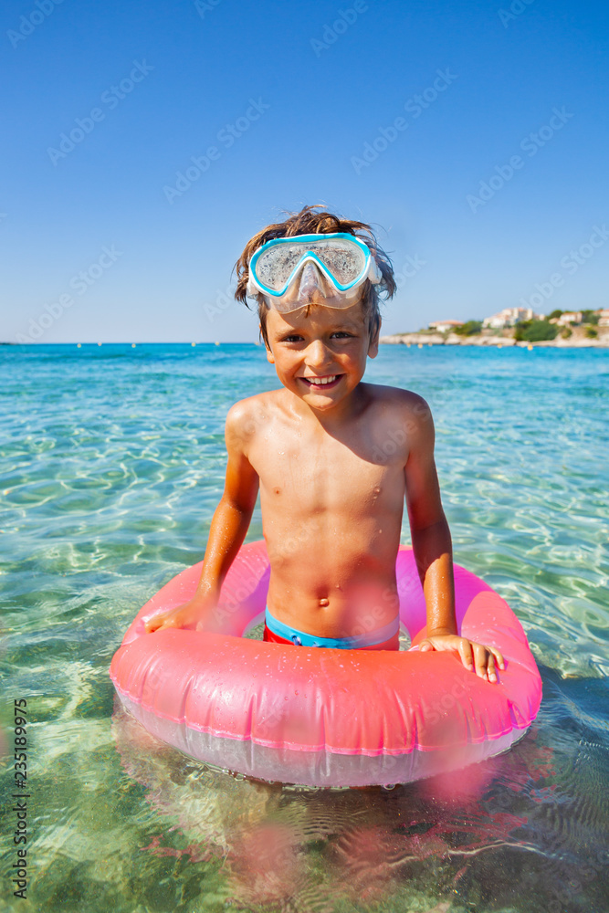 戴着水肺面罩和游泳圈的男孩在海水中
