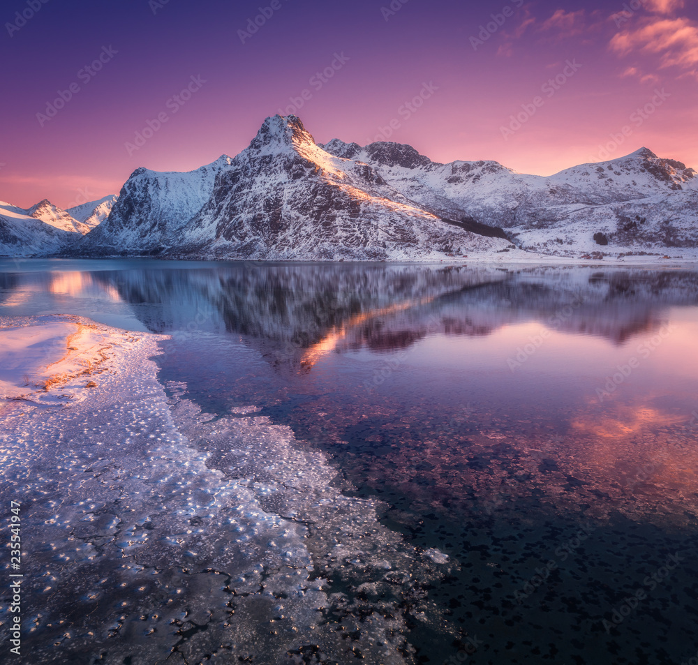 雪山鸟瞰图，蓝色的大海和霜冻的海岸，水中的倒影和紫色的天空。
