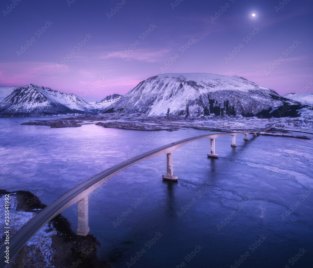 桥的鸟瞰图，白雪皑皑的山脉，紫色的天空，云和月亮，水中的倒影。