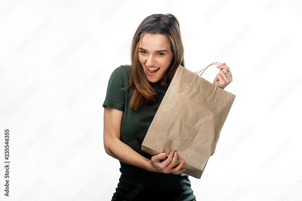 Portrait of smiling dark-haired woman with shopping bag in her hands. Young happy girl holding paper