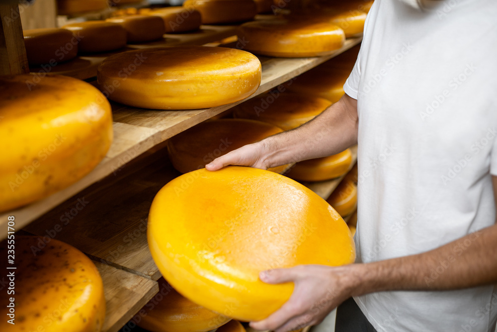 奶酪陈化过程中，工人在仓库拿奶酪轮。无fac的特写