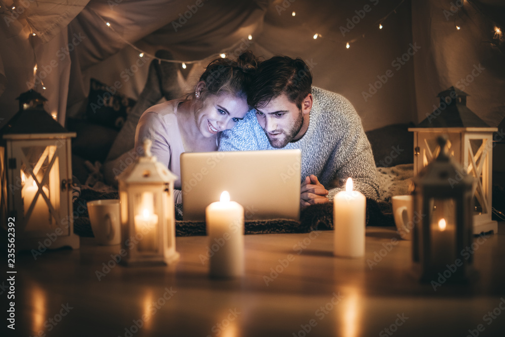 一对夫妇躺在床上看着笔记本电脑