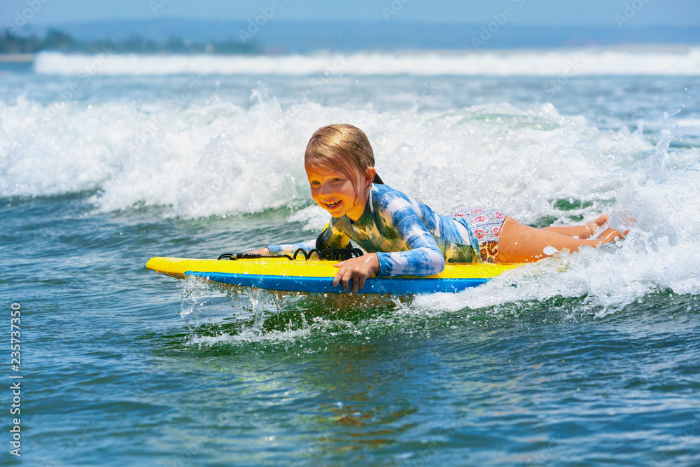 快乐的女婴-年轻的冲浪者在冲浪板上冲浪，在海浪上玩得很开心。孩子，积极的家庭生活方式