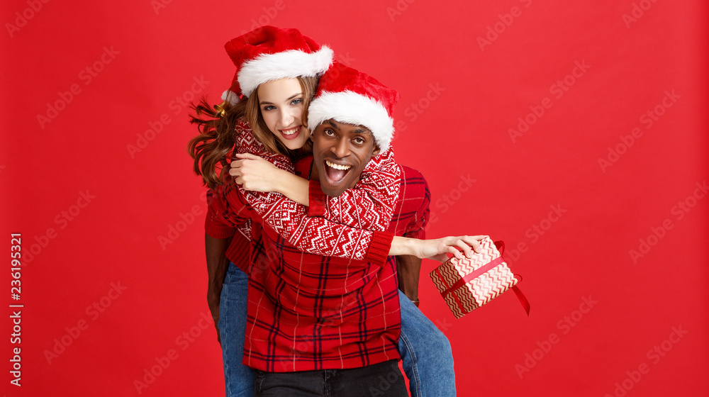 幸福的一对黑人男子和高加索女子戴着红底圣诞帽