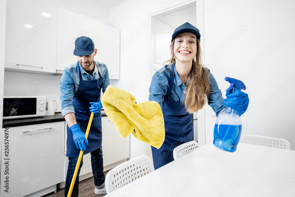 一对男女在白色公寓里用清洁工具作为专业清洁工的有趣画像
