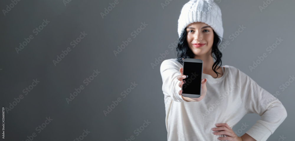 一名年轻女子在灰色背景下手持手机