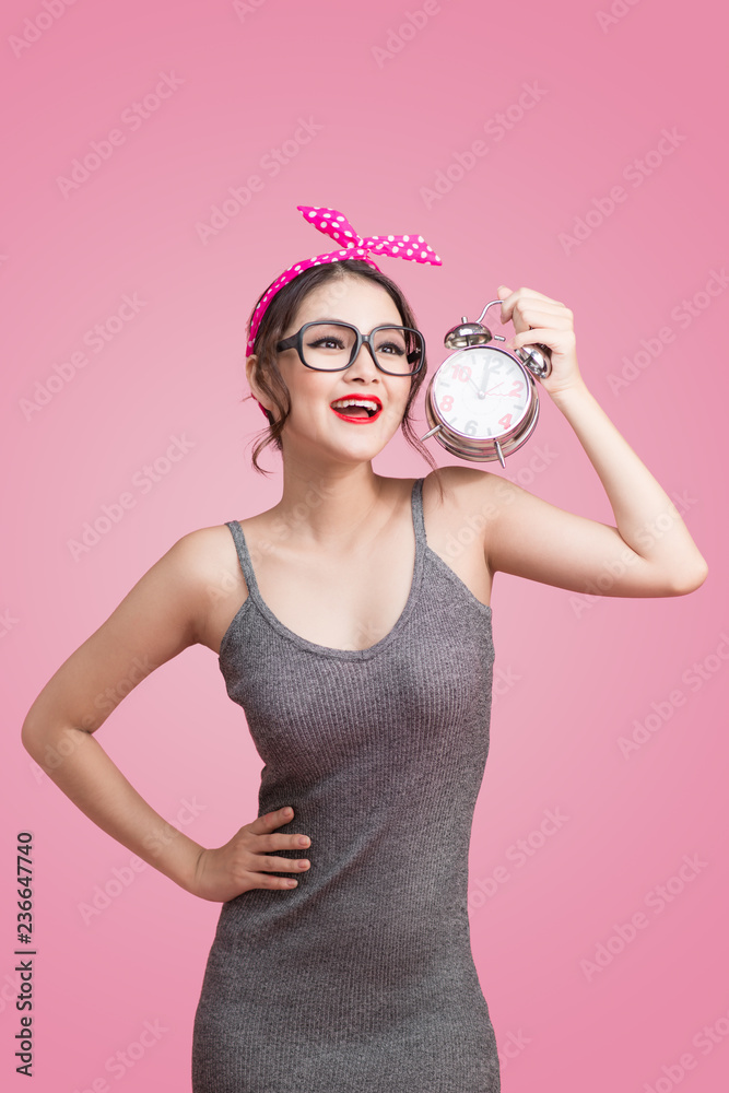 美丽微笑的亚洲年轻女子展示粉色闹钟