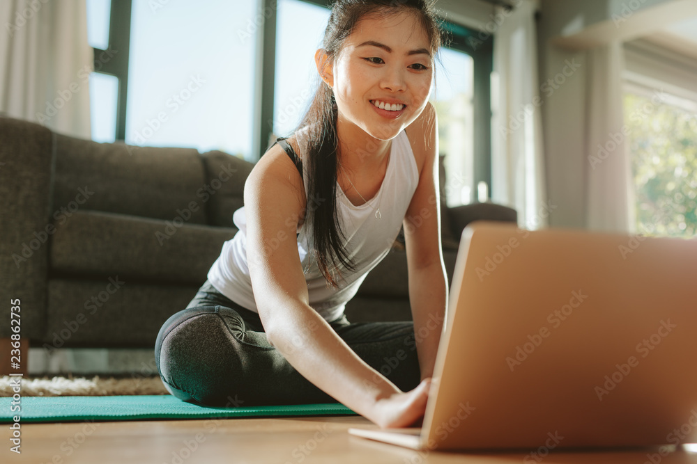 女性在家锻炼时使用笔记本电脑