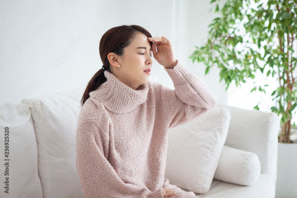 自宅で頭痛と発熱に悩む女性