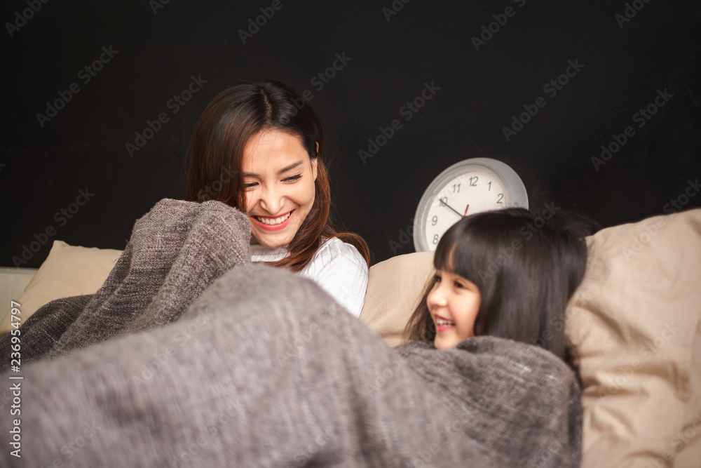 幸福的亚洲家庭——躺在卧室床上的母女在睡觉前说晚安