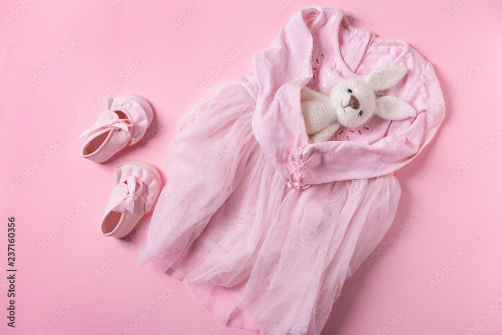 彩色背景的婴儿连衣裙、鞋子和玩具，俯视图