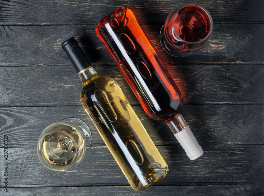 深色木质背景上装有不同种类葡萄酒的瓶子和玻璃杯