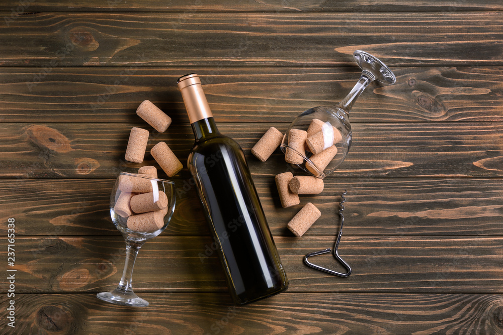 木制背景的带软木塞和玻璃杯的葡萄酒瓶