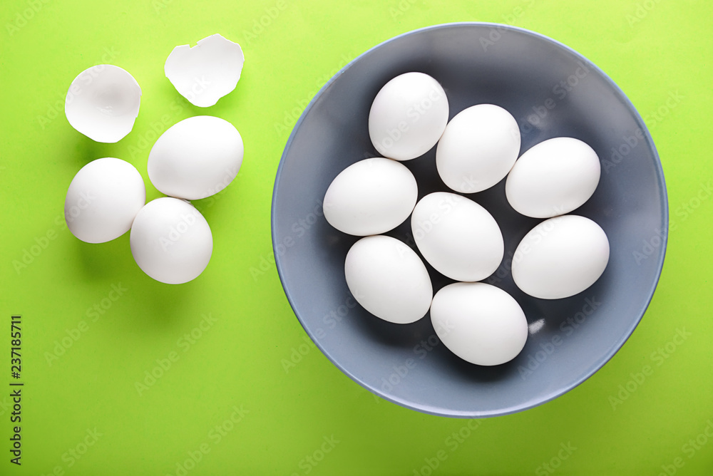 Plate with raw chicken eggs on color background