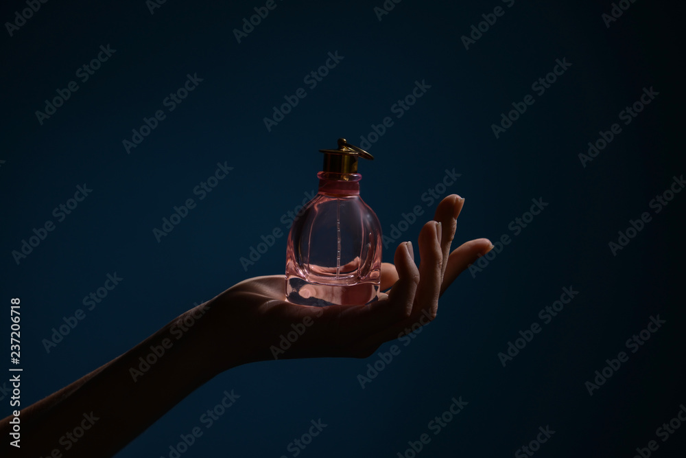 女人拿着一瓶深色背景的香水