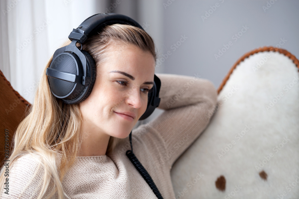 戴着耳机在家听音乐放松的年轻女性