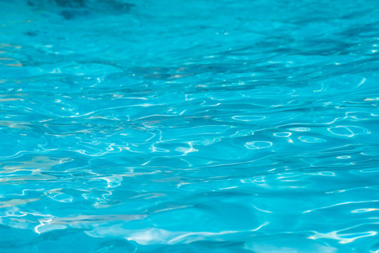 游泳池湛蓝明亮的水面和阳光反射的涟漪