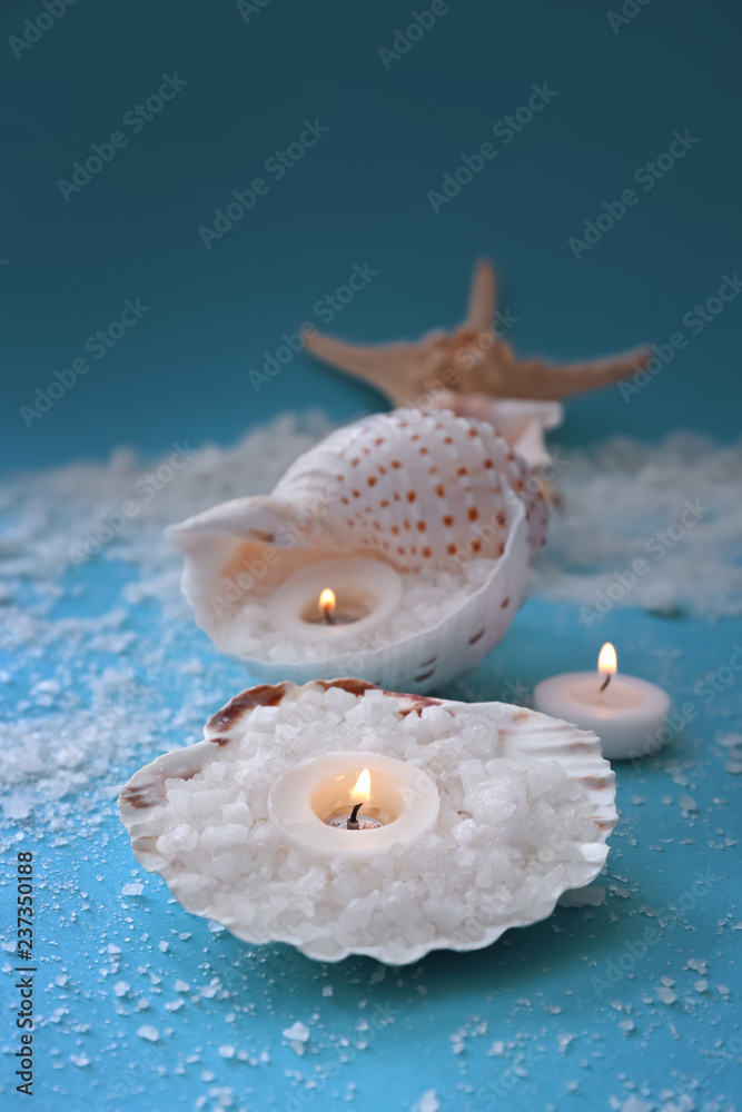 用贝壳和海盐在彩色桌子上燃烧蜡烛