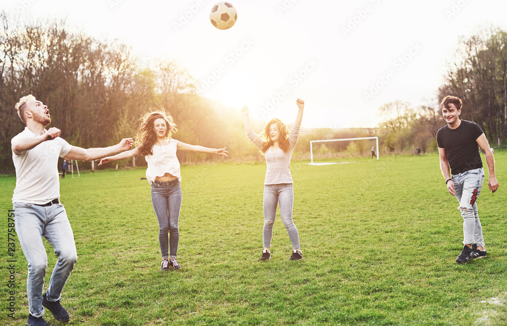 A group of friends in casual outfit play soccer in the open air. People have fun and have fun. Activ