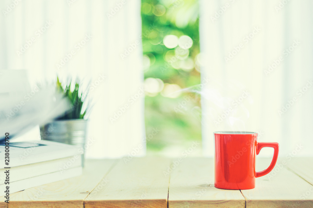 木桌面上的一杯咖啡和窗帘与窗户背景的模糊