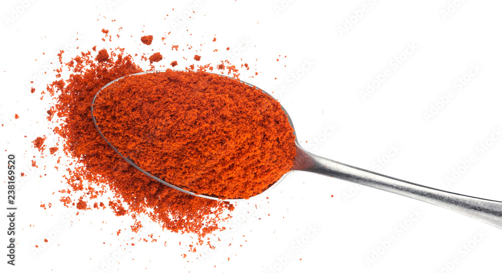 白色背景上分离的勺子里的磨碎的红色辣椒粉。俯视图