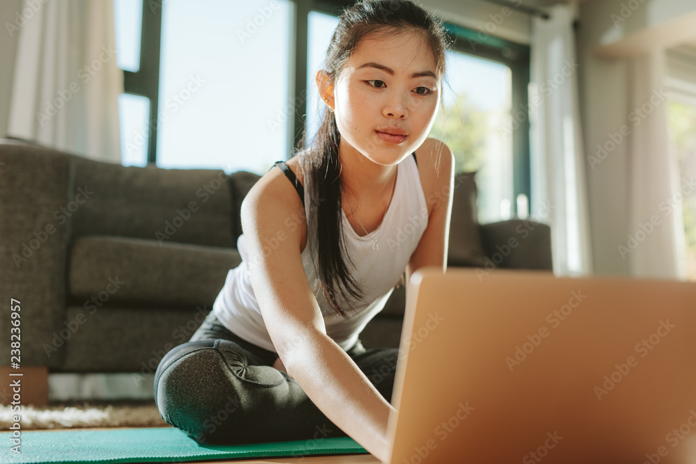 女人在家里用笔记本电脑看健身视频