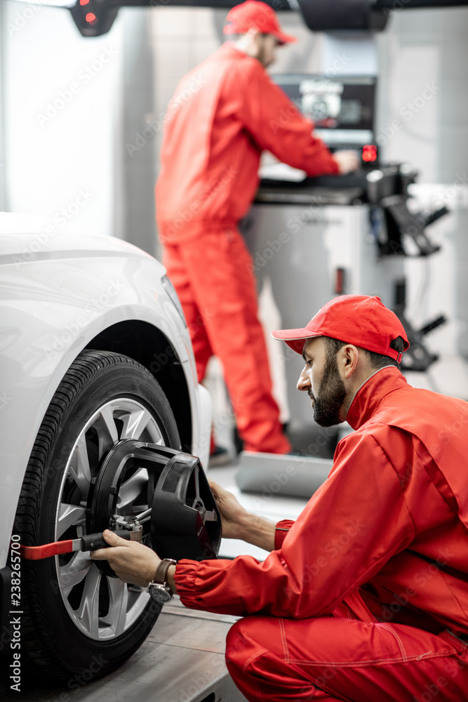 英俊的红色汽车修理工，用于汽车维修处的车轮定位的统一固定盘