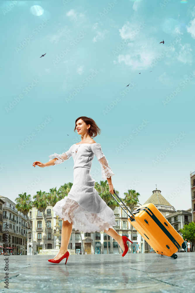 一位年轻漂亮的女士来到西班牙度假。她带着行李箱旅行得很开心。
