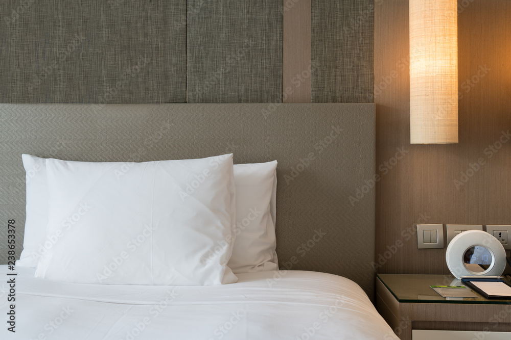 现代家庭或酒店中带阅读灯和数字闹钟的卧室的特写片段。