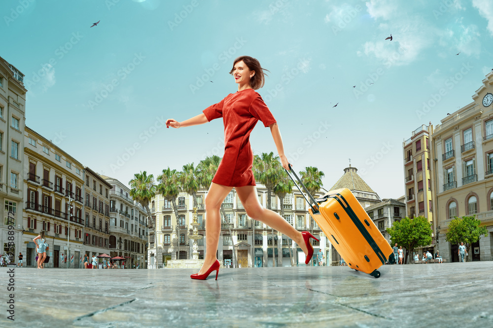 一位年轻漂亮的女士来到西班牙度假。她带着行李箱非常开心地旅行。