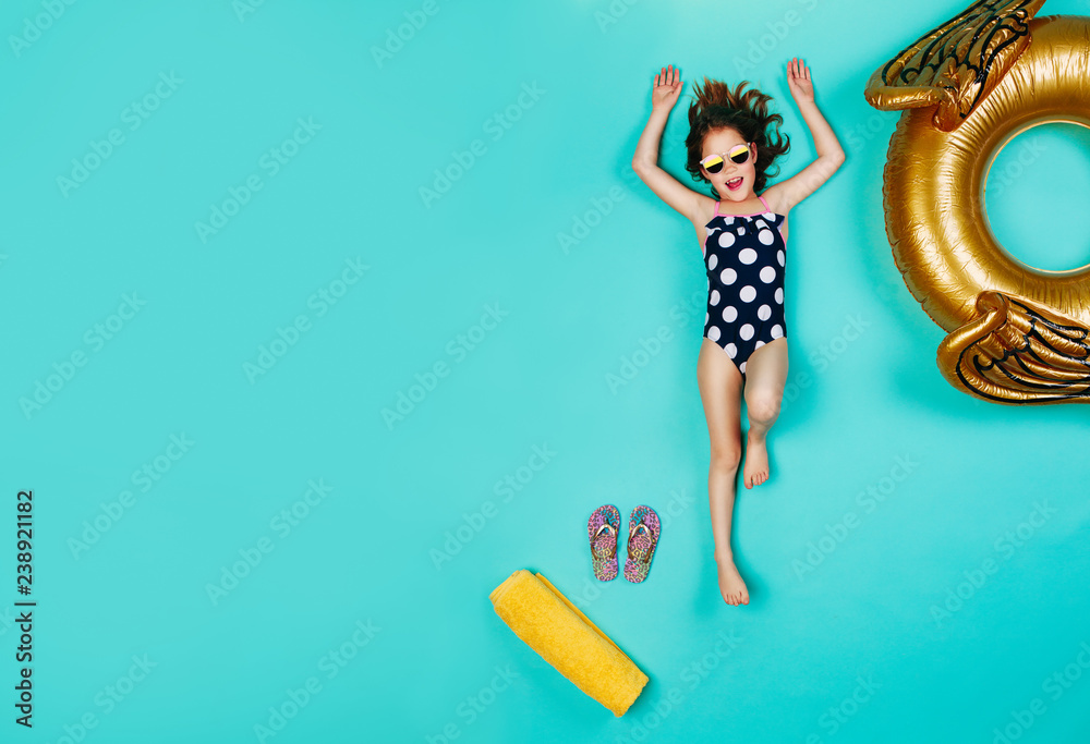 Happy girl in swimsuit lying on blue background