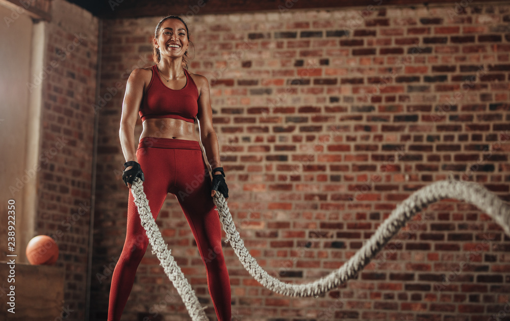 微笑的女人用战斗绳锻炼身体