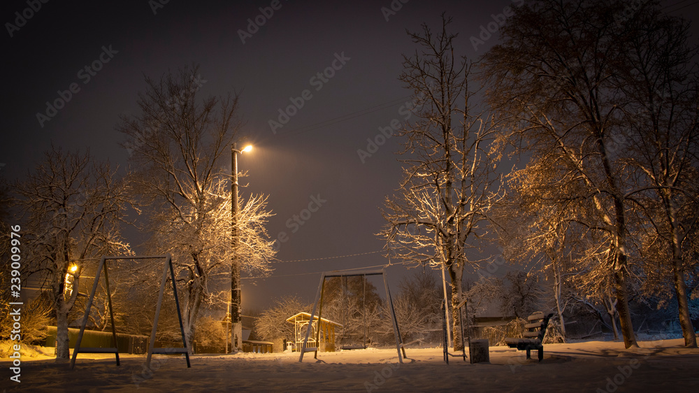 美丽的乡村冬季白雪覆盖的街道上挂着灯笼。汽车照亮了小路