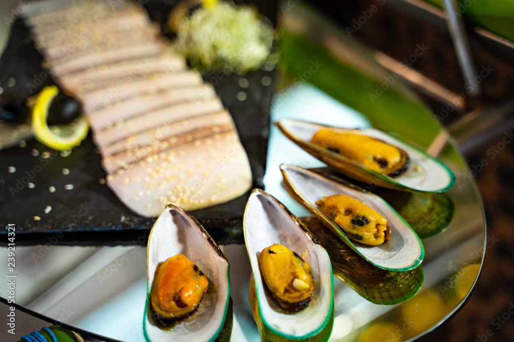 海鲜。在玻璃桌上烤贝壳牡蛎和切成薄片的异国情调的肉。客人的开胃菜