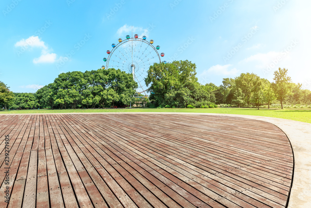 绿色城市公园的空木板广场和摩天轮
