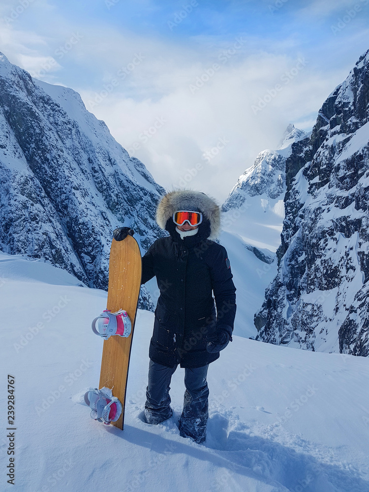 在落基山脉的滑雪道上，一个快乐的女人站在她的滑雪板旁边。