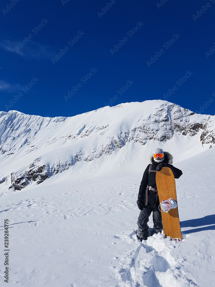 极限女子单板滑雪运动员在攀登雪山前用滑雪板摆姿势。