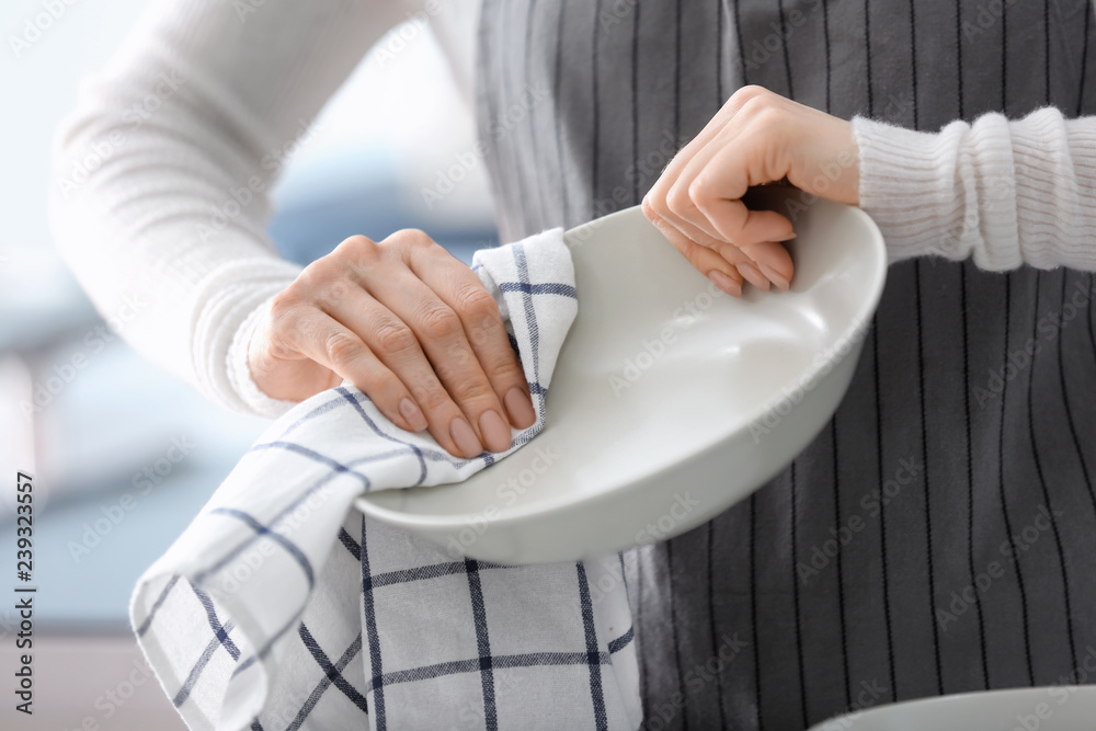 妇女在厨房用毛巾擦盘子