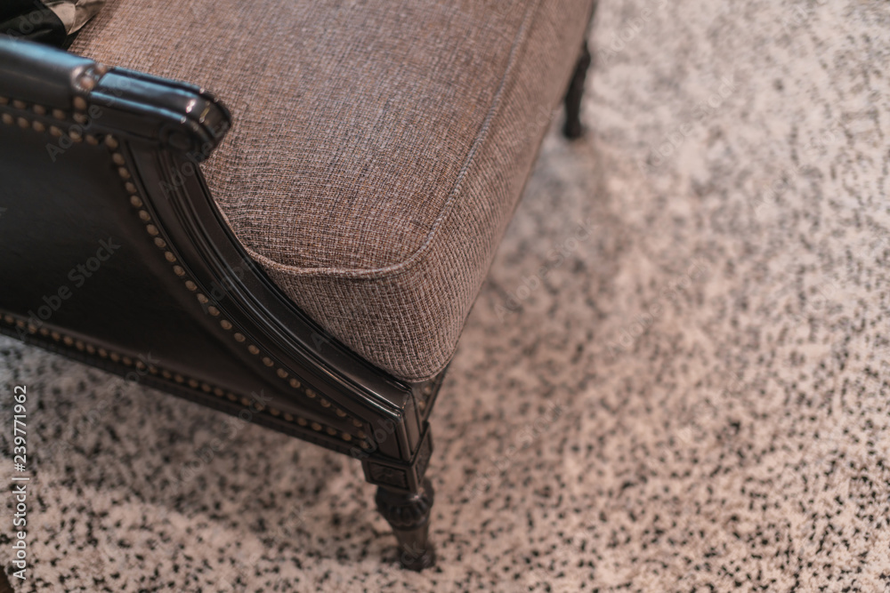 detail of armchair leg close up with carpet rug under furniture
