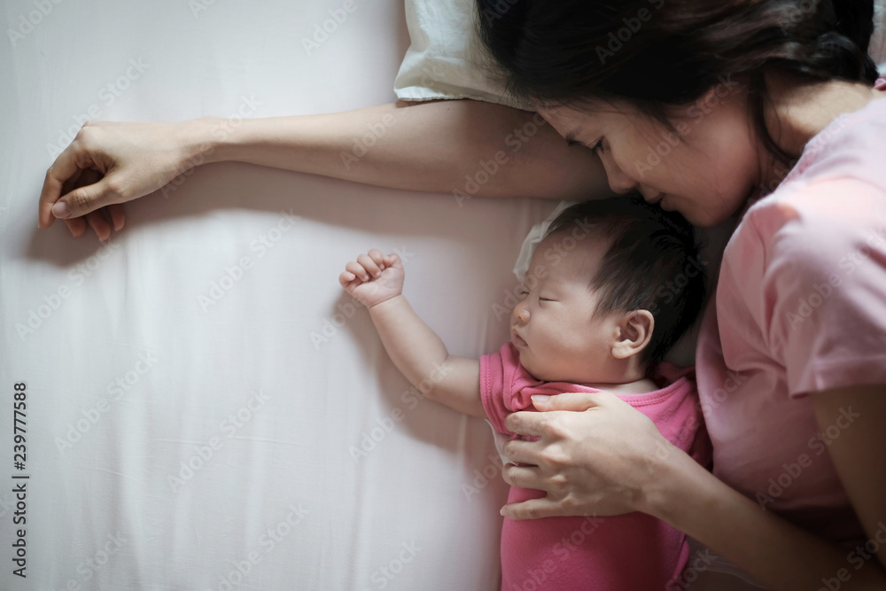 美丽年轻的亚洲母亲亲吻熟睡的新生儿的特写照片