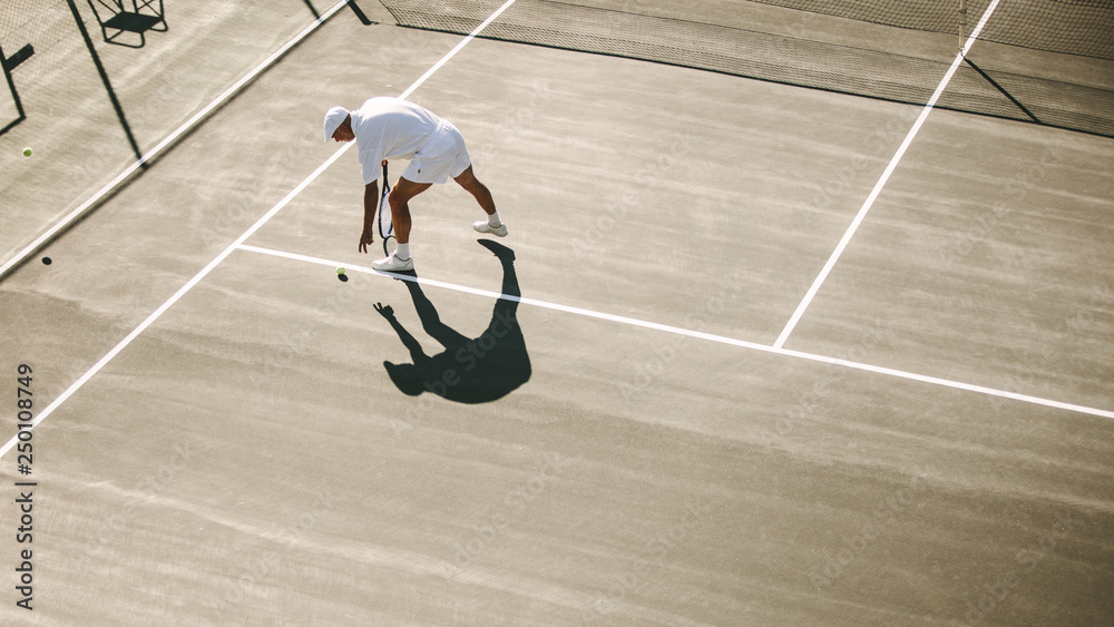 一名资深男子在一场网球比赛中弯腰捡网球