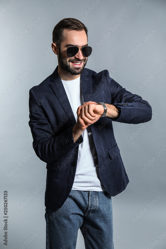 灰色背景下的英俊时尚男士看手表
