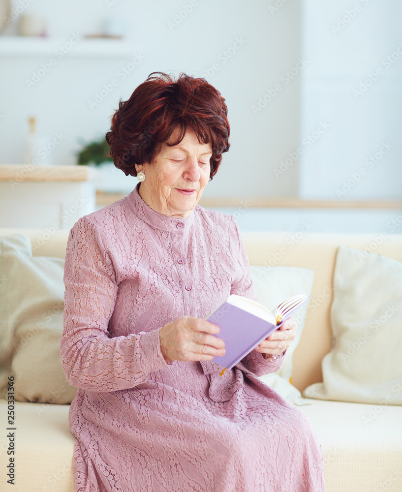 美丽的成熟女性（80岁）坐在家里的沙发上，与伟人一起读书的肖像