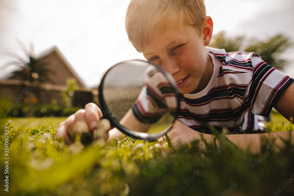 Boy exploring garden with his magnifying glass