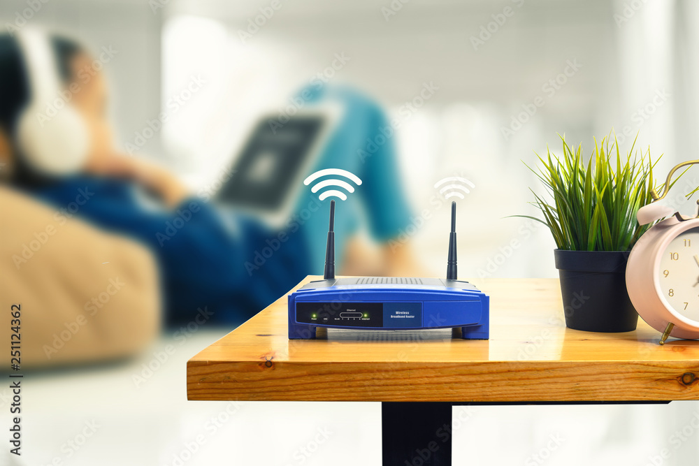 一个无线路由器和一名男子在家中客厅使用智能手机的特写