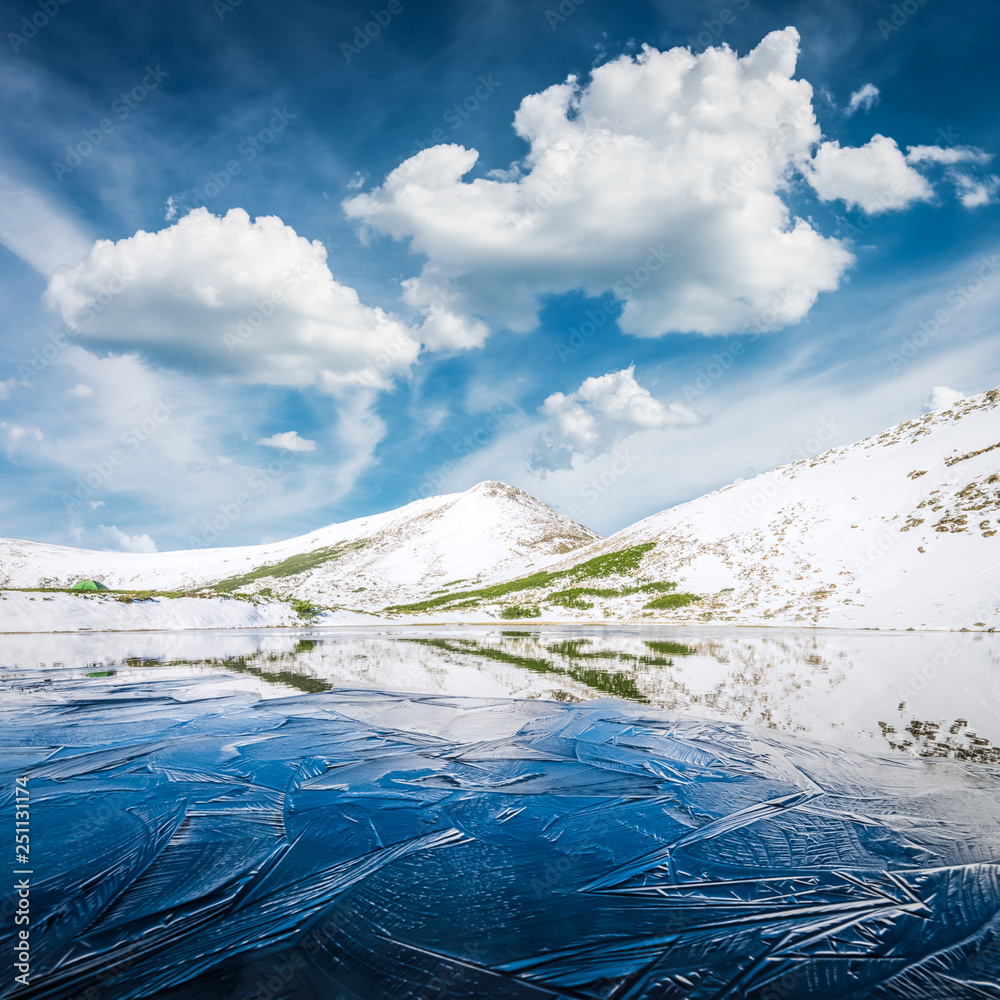结冰的山湖，表面有蓝色的冰和裂缝。冬季雪景如画