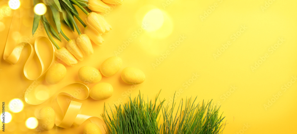 复活节背景。明亮的黄色鸡蛋和黄色背景上一束春天盛开的郁金香