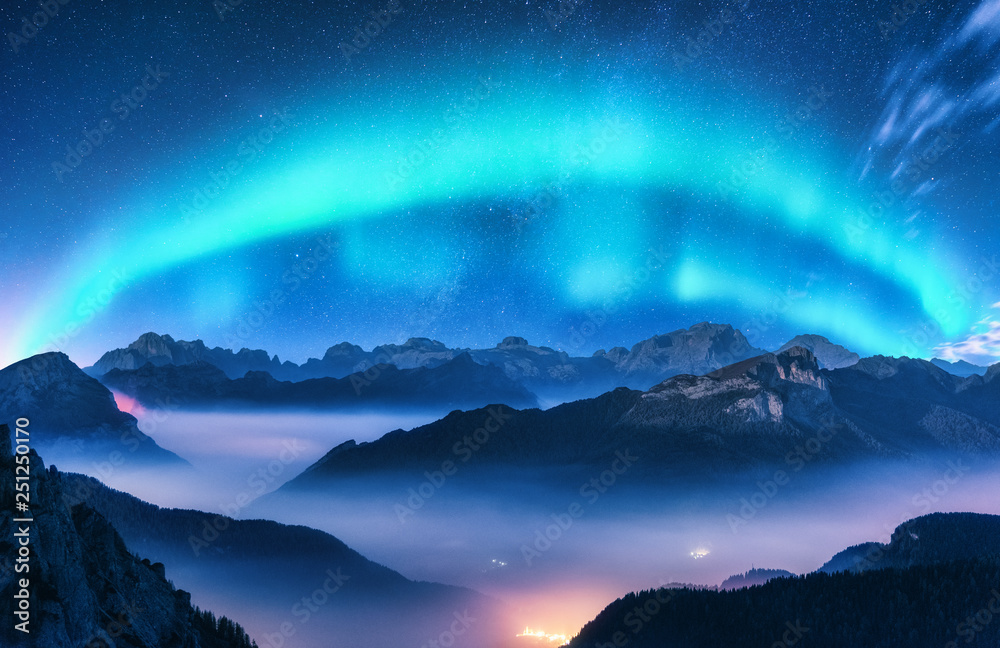 夜晚雾蒙蒙的北极光笼罩在群山之上。北极光。天空中有星星和极光。