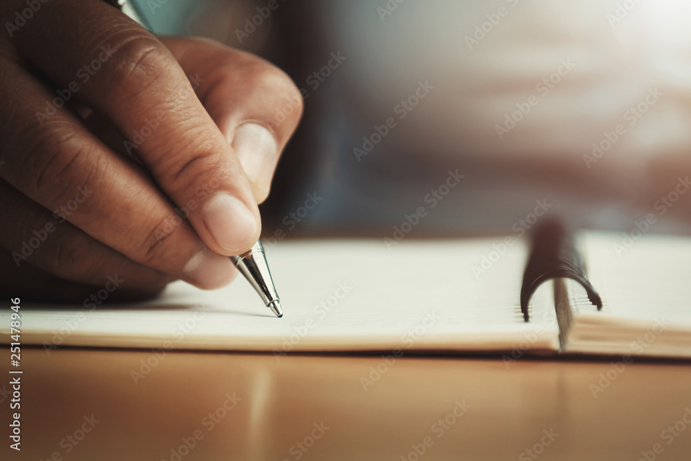 办公室里拿着钢笔在笔记本上写字的女人的手