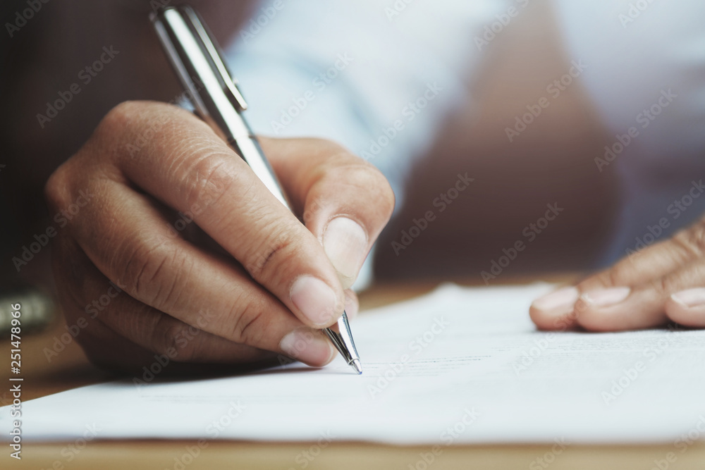 办公室里拿着钢笔在纸上写报告的女人的手